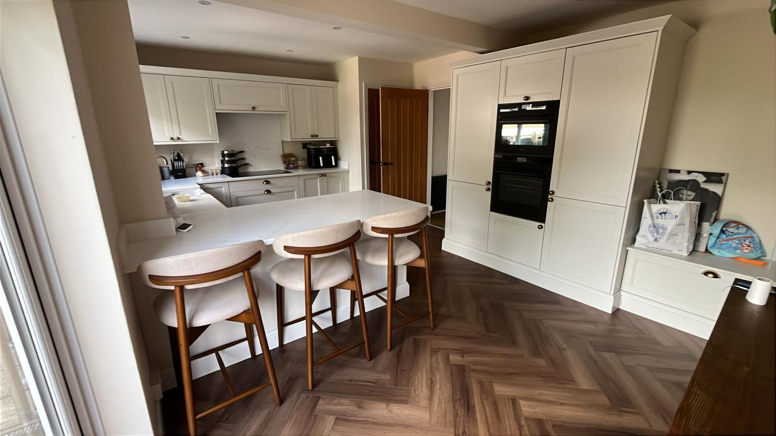 Kitchen installation with island, fitted cabinets and herringbone floor